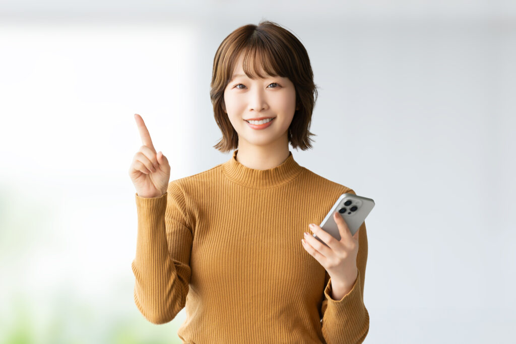 スマホを持って指を立てる女性