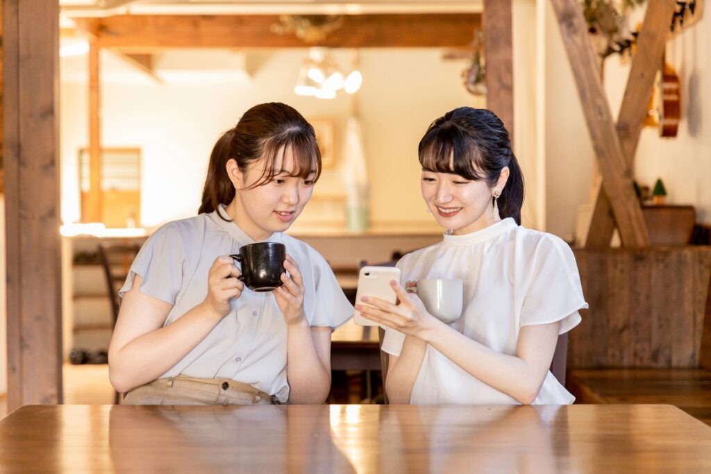 カフェでスマホを見ながら話す女性