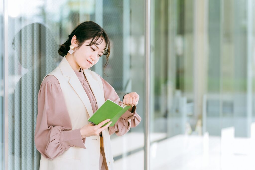 腕時計で時間を見て手帳を確認する女性