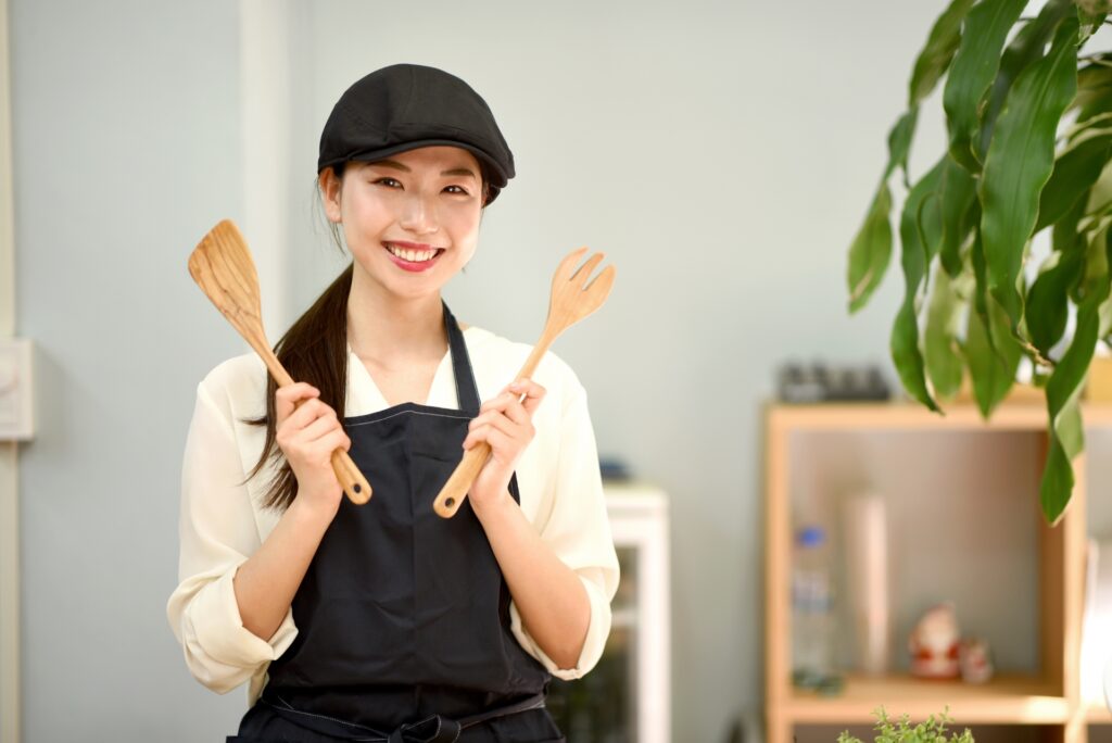キッチン用品を持つエプロン姿の女性