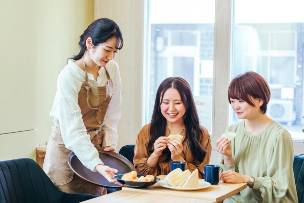 レストランで食事する女性とホールスタッフ