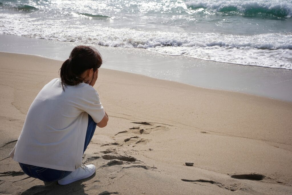 海辺で悩む女性