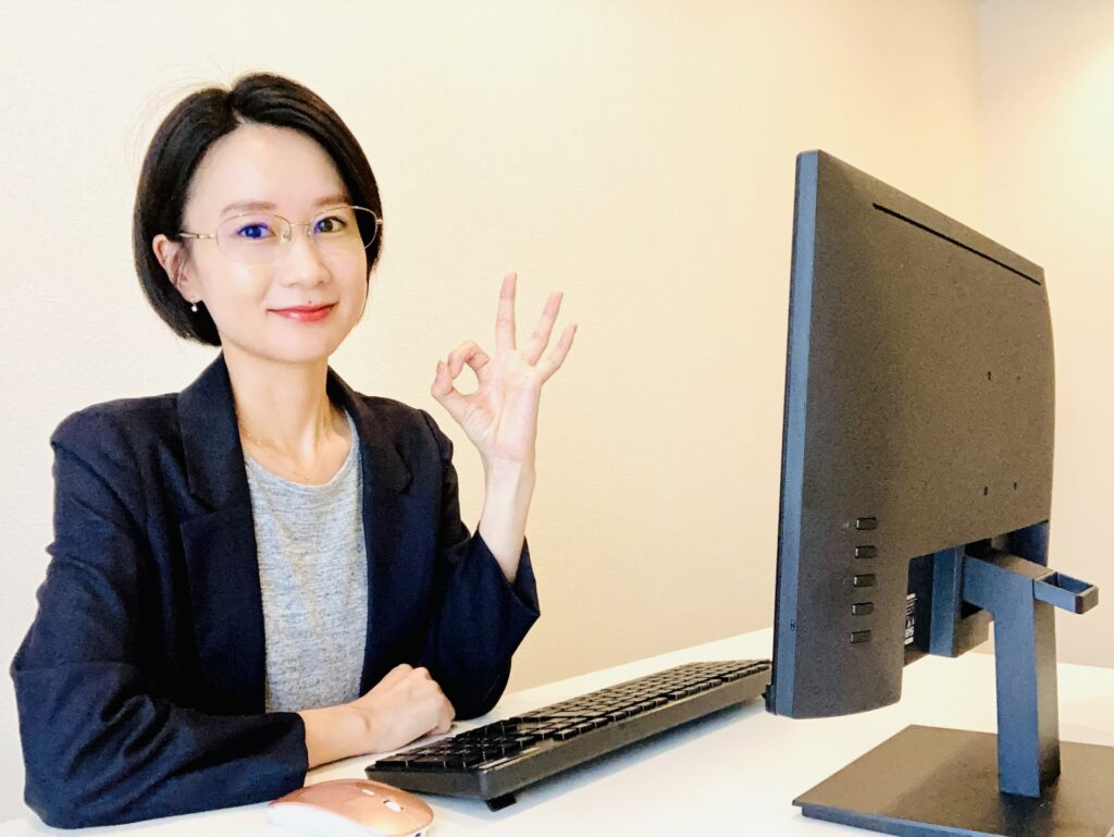 パソコンの前に座るOKサインをする女性