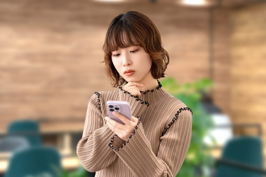 スマホを見ながら考える女性