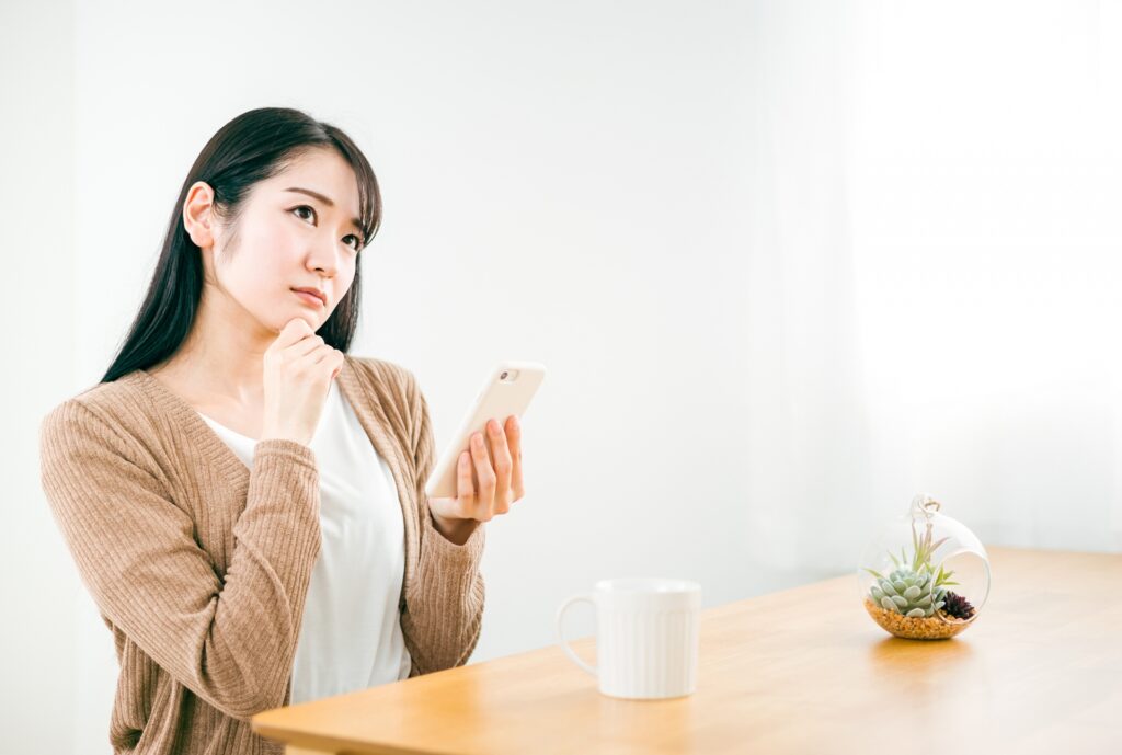 スマホを見て考える女性