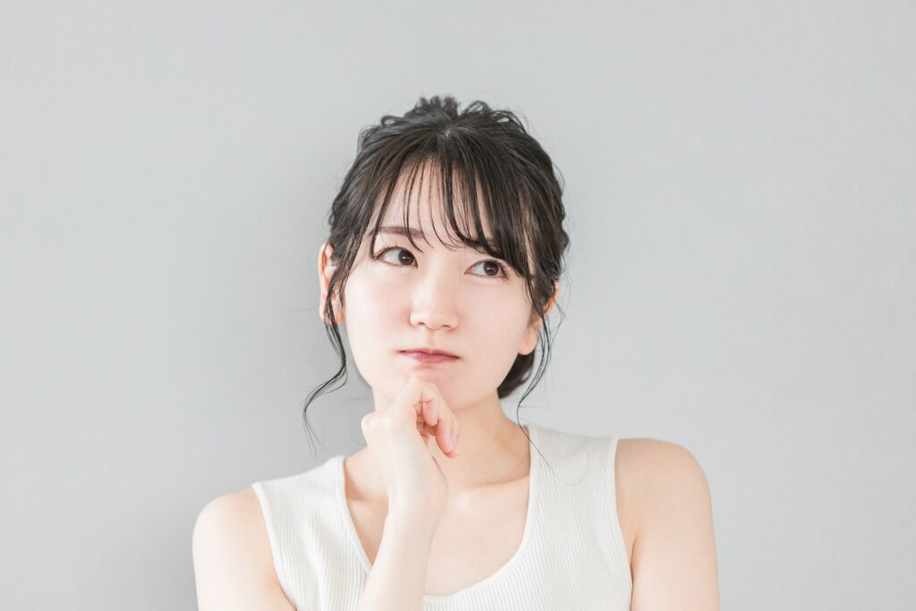 頬杖をついて考える・悩むアジア人女性