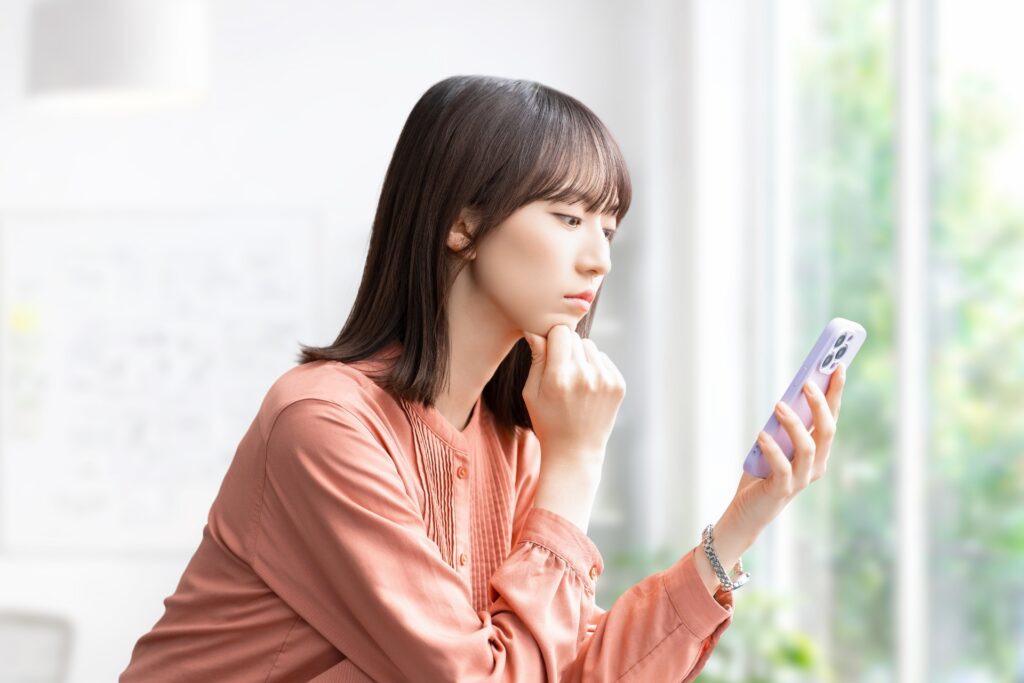 スマホを見て考えごとをする女性